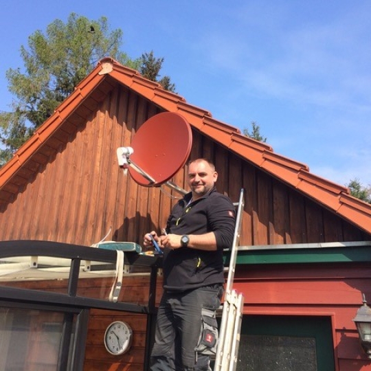 Herr Schulz installiert eine Satellitenschüssel.