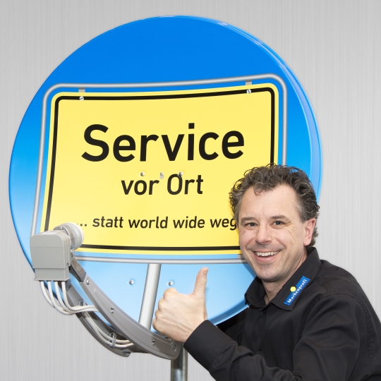 Herr Schindel posiert vor einem Satelliten.
