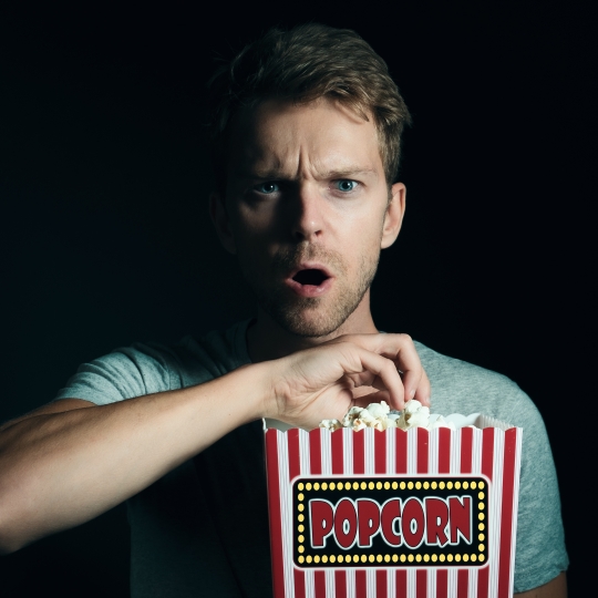 Eine Person schaut geschockt, während sie Popcorn isst.