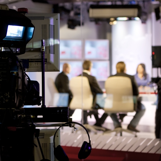 Eine Kamera filmt 4 Personen bei einer Talkshow.