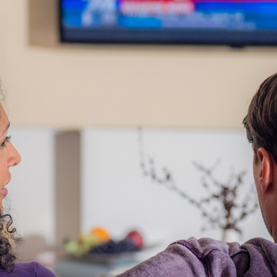 Zwei Personen vor einem Fernseher. 