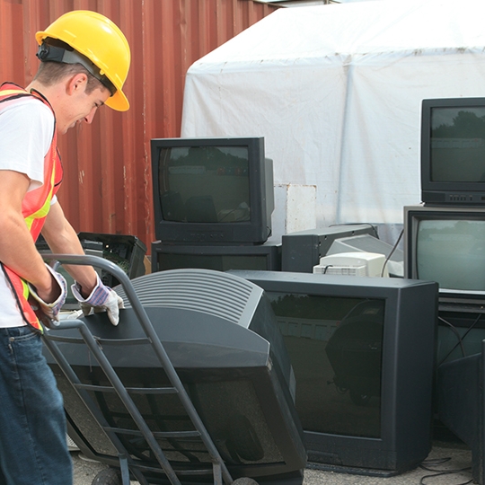 Eine Person entsorgt alte Fernseher. 