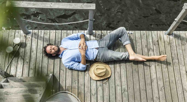 Eine Person schläft entspannt auf einem Deck.