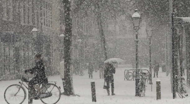 Eine Fußgängerzone, mit fallendem Schnee und Menschen, die unterwegs sind.