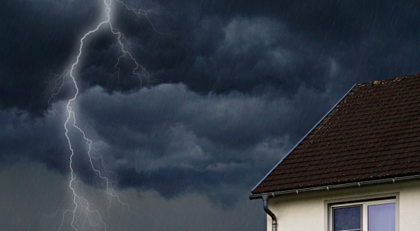 Ein Haus während eines Gewitters, bei dem ein Blitz neben das Gebäude einschlägt.
