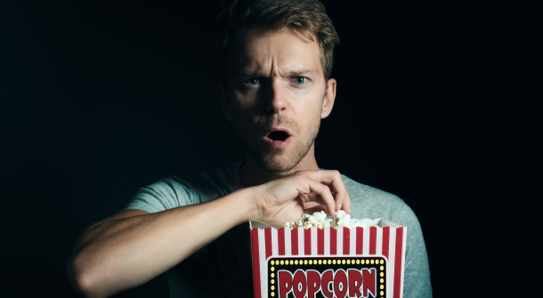 Eine Person schaut geschockt, während sie Popcorn isst.