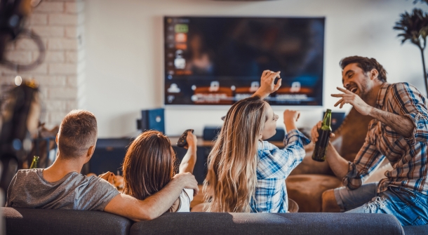 Vier Personen lachend vorm Fernseher.