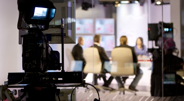 Eine Kamera filmt 4 Personen bei einer Talkshow.