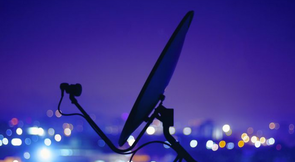 Eine Satellitenschüssel von der Seite bei Nacht.