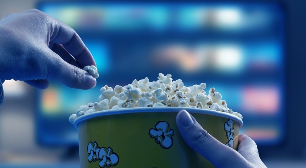 Ein Popcorn Kübel vor einem Fernseher.